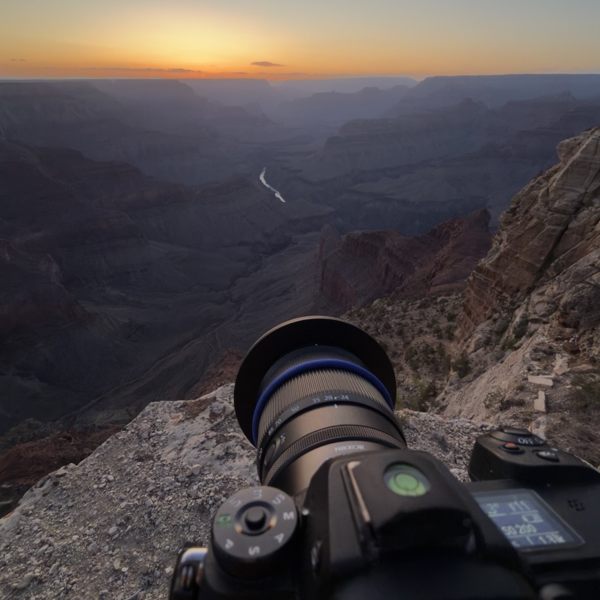 Point of view over a camera lens at blue hour, the Colorado River winding through the canyon below