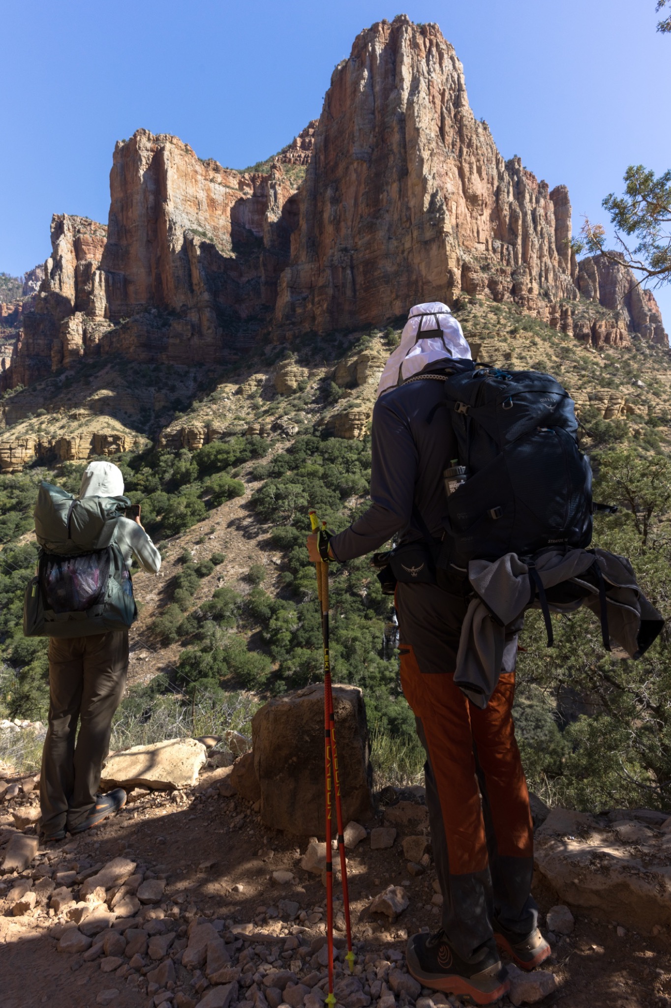 Two backpackers looking up at a sunlit butte from the trail in the Grand Canyon
