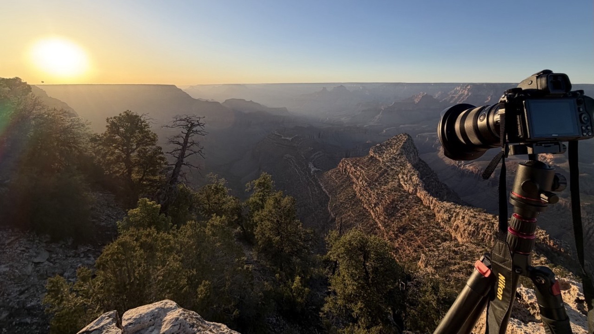 Camera on a tripod at Grandview Point at sunrise, sun flaring over the Grand Canyon