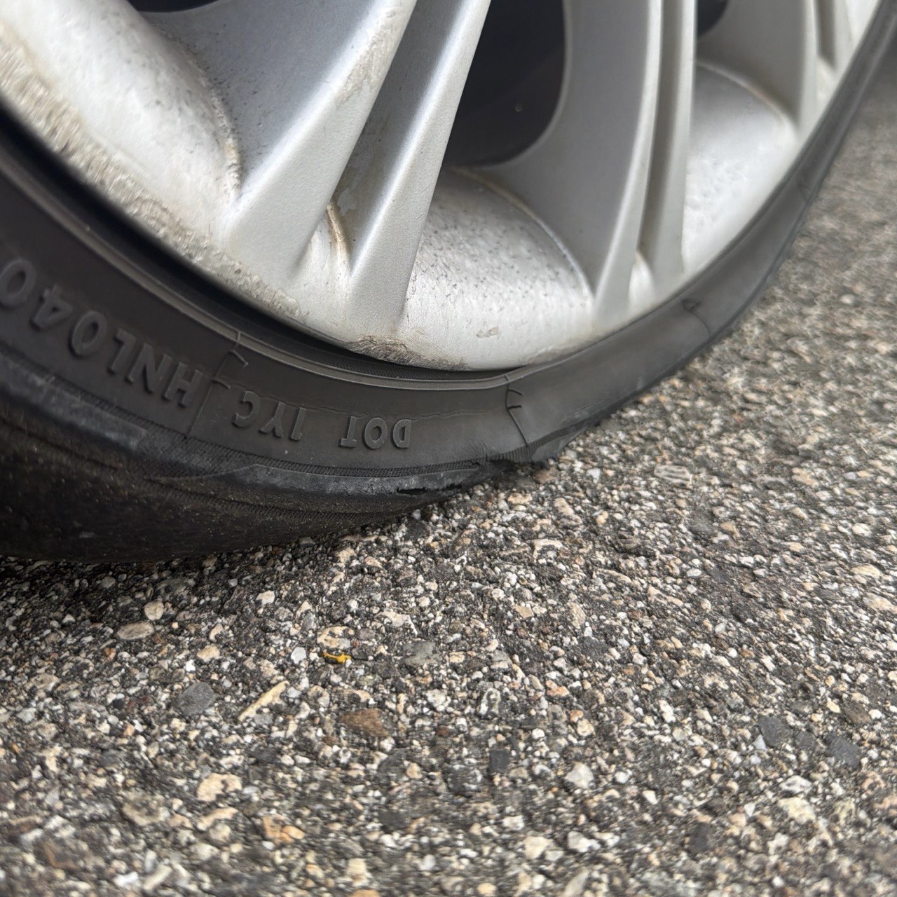 Close-up of a car tire with a sidewall cut, flat on the asphalt beside White Mountain Road below Grandview Campground