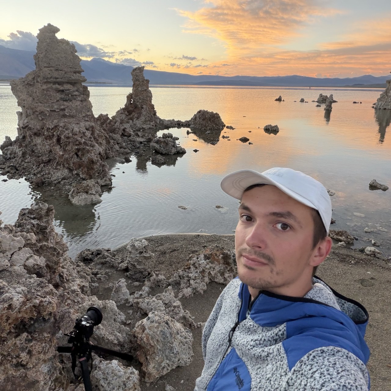 Danil Zanozin at South Tufa, Mono Lake, at sunset with a camera on a low tripod behind the tufa towers, pink clouds reflected in the lake