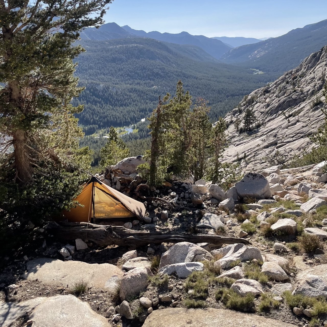 Backpacking tent pitched on a rocky ledge above the Evolution Lake outlet waterfall on the John Muir Trail