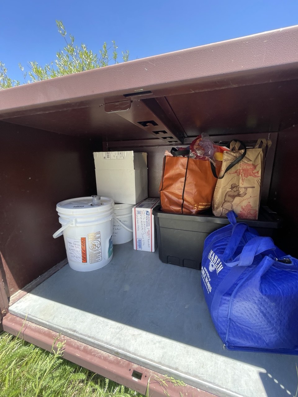 Bear box at Onion Valley campground holding hikers' resupply caches including a small USPS box, for a John Muir Trail thru-hike