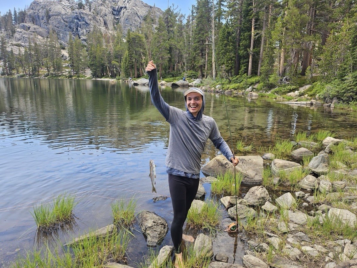 Hiker holding up his first caught trout at Rosalie Lake in the Ansel Adams Wilderness on the John Muir Trail