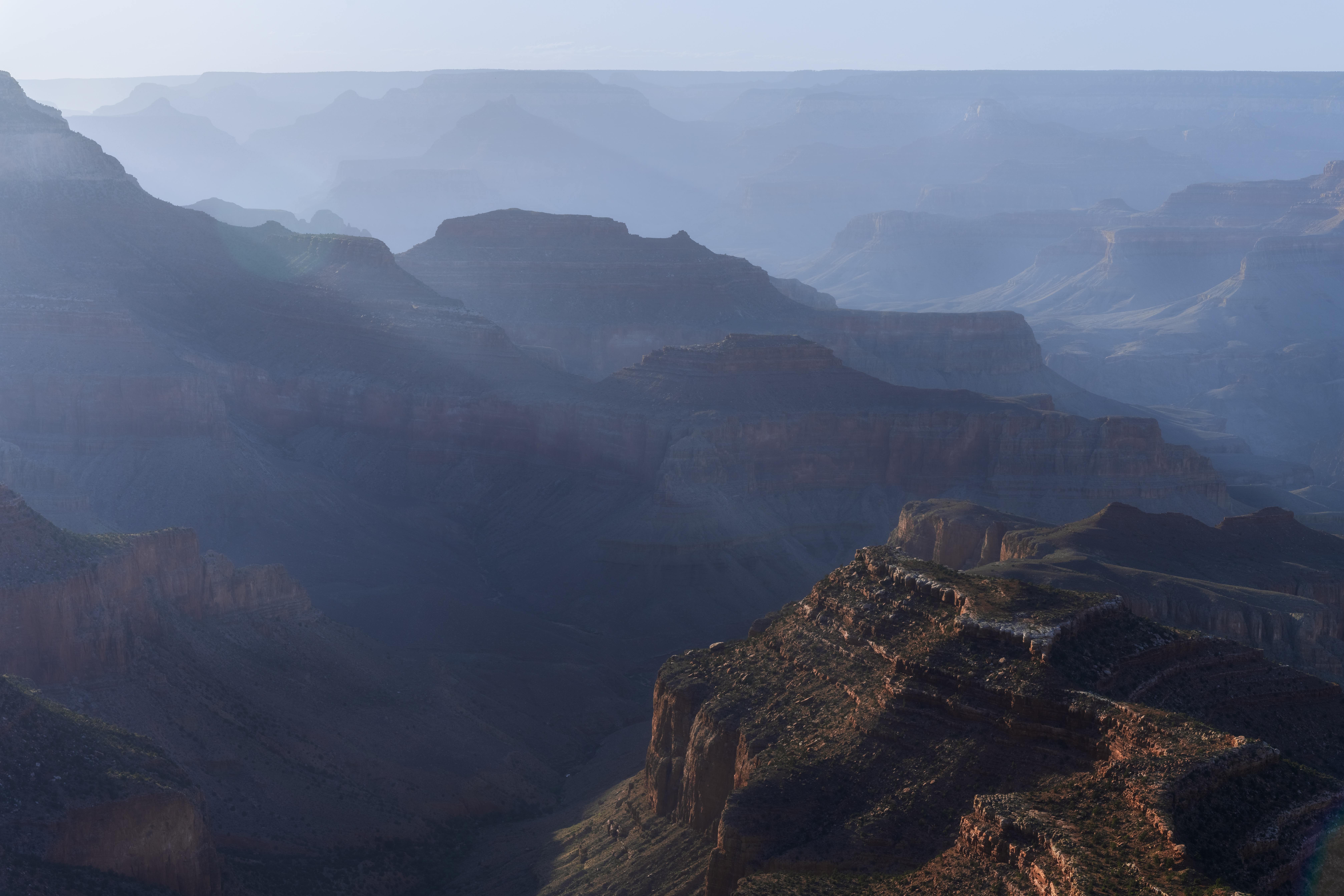Sunlight on Berry Butte, rising from the hazy blue ridges of the Grand Canyon at Grandview Point.